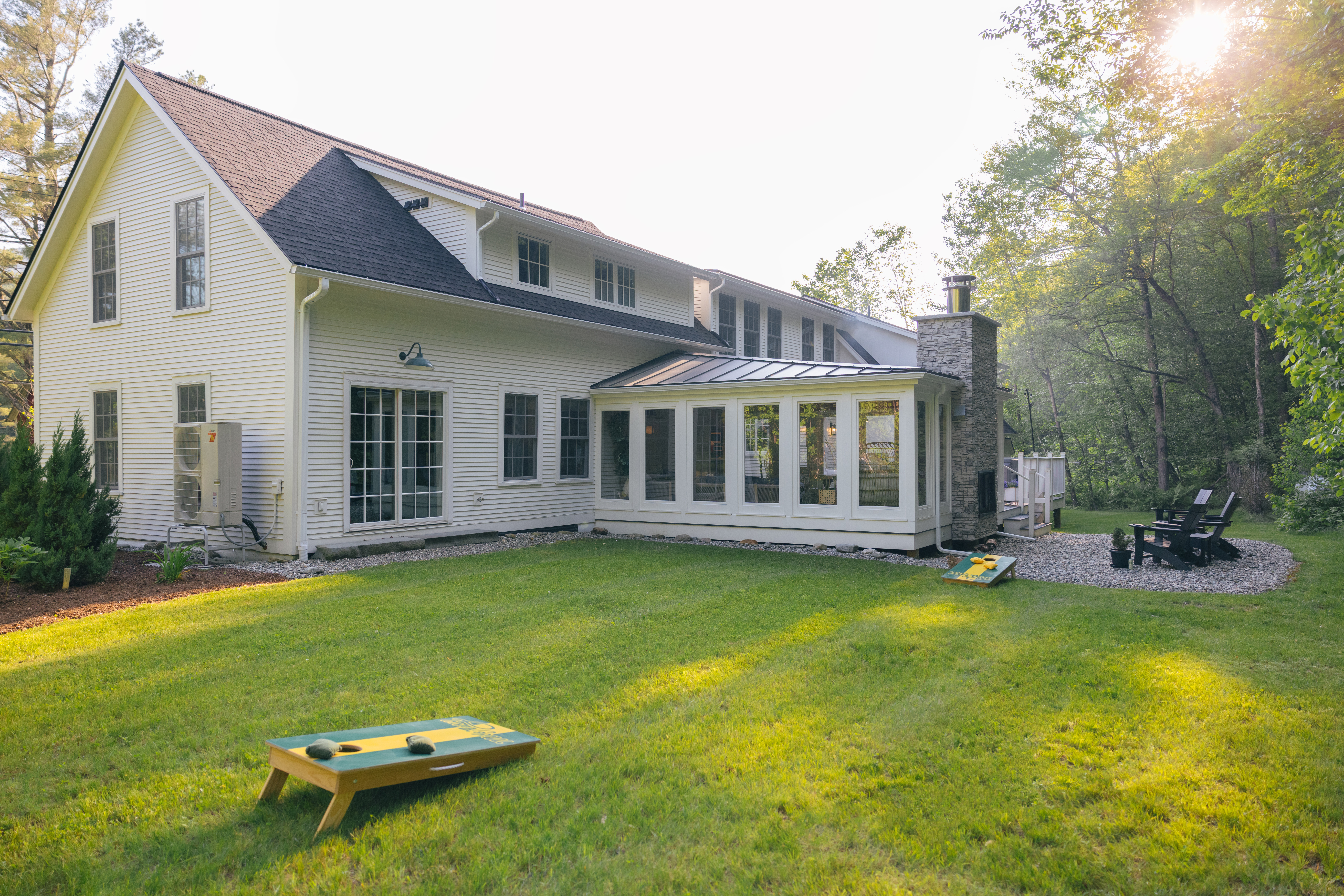 Back facade of Mile Away Victorian farmhouse in Stowe, Vermont, showing the house exterior and back lawn